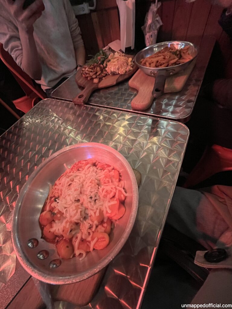 Tomato gnocchi and cheese in a pan and other food on the other side of the table.