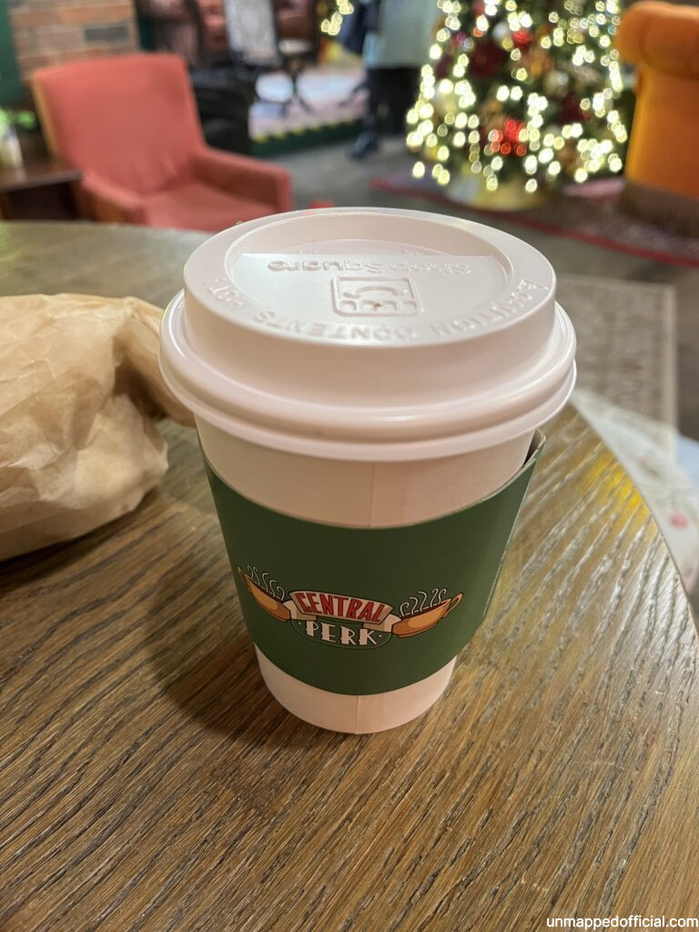a disposable coffee cup with a lid. Christmas tree in the background