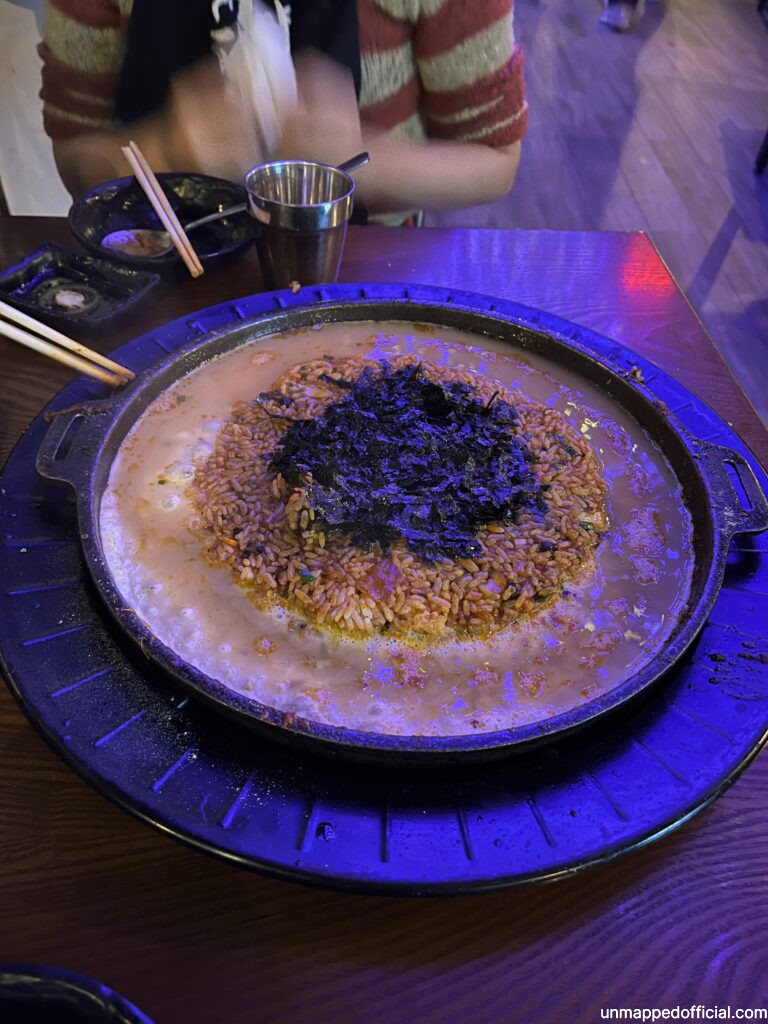 a large cast iron pan with fried rice, surrounded by egg and topped with seaweed flakes.
