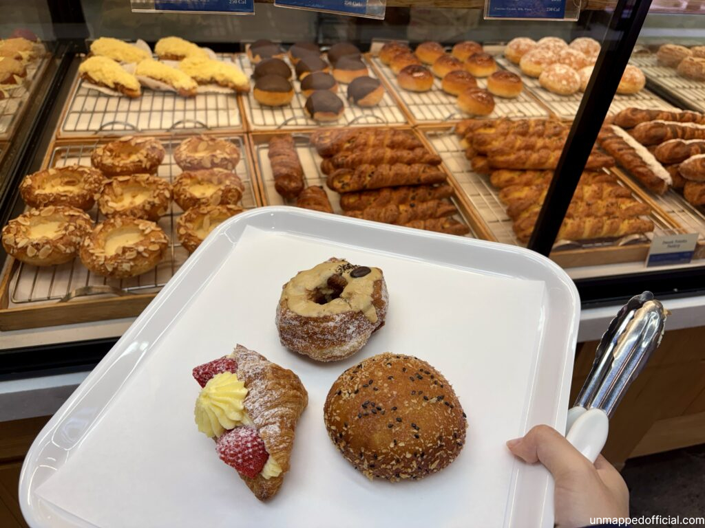 3 pastries on a tray with a display box of pastries in the background
