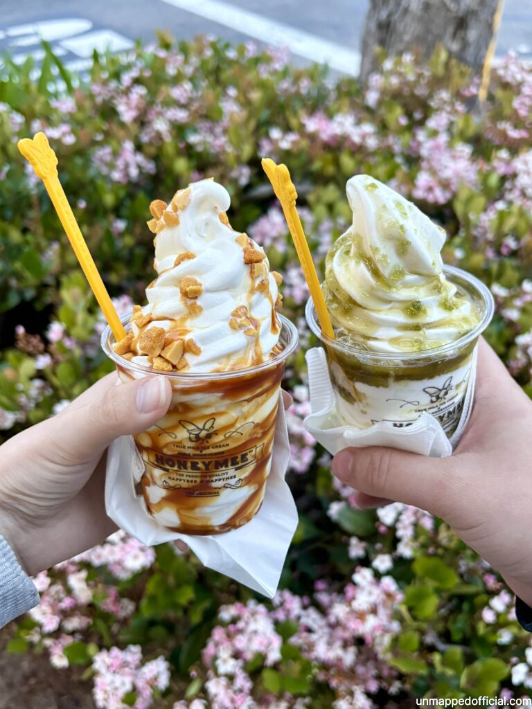 holding two ice creams from honeymee with shrub in background