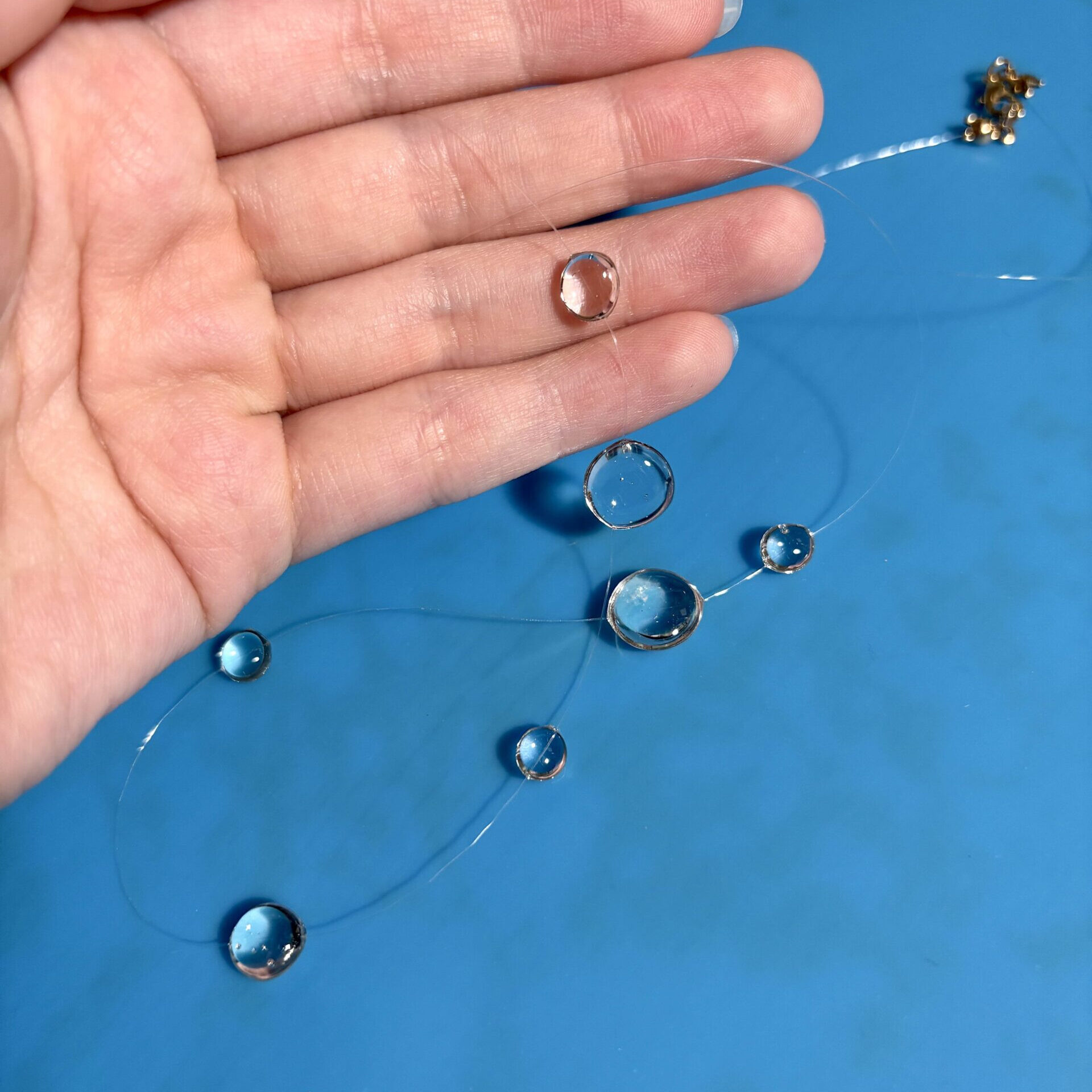 holding finished resin raindrop necklace on the nylon thread